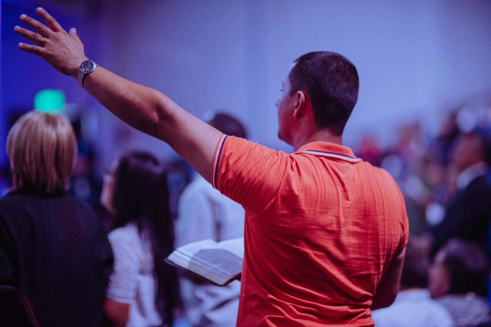 A man in an orange shirt is holding his hands up